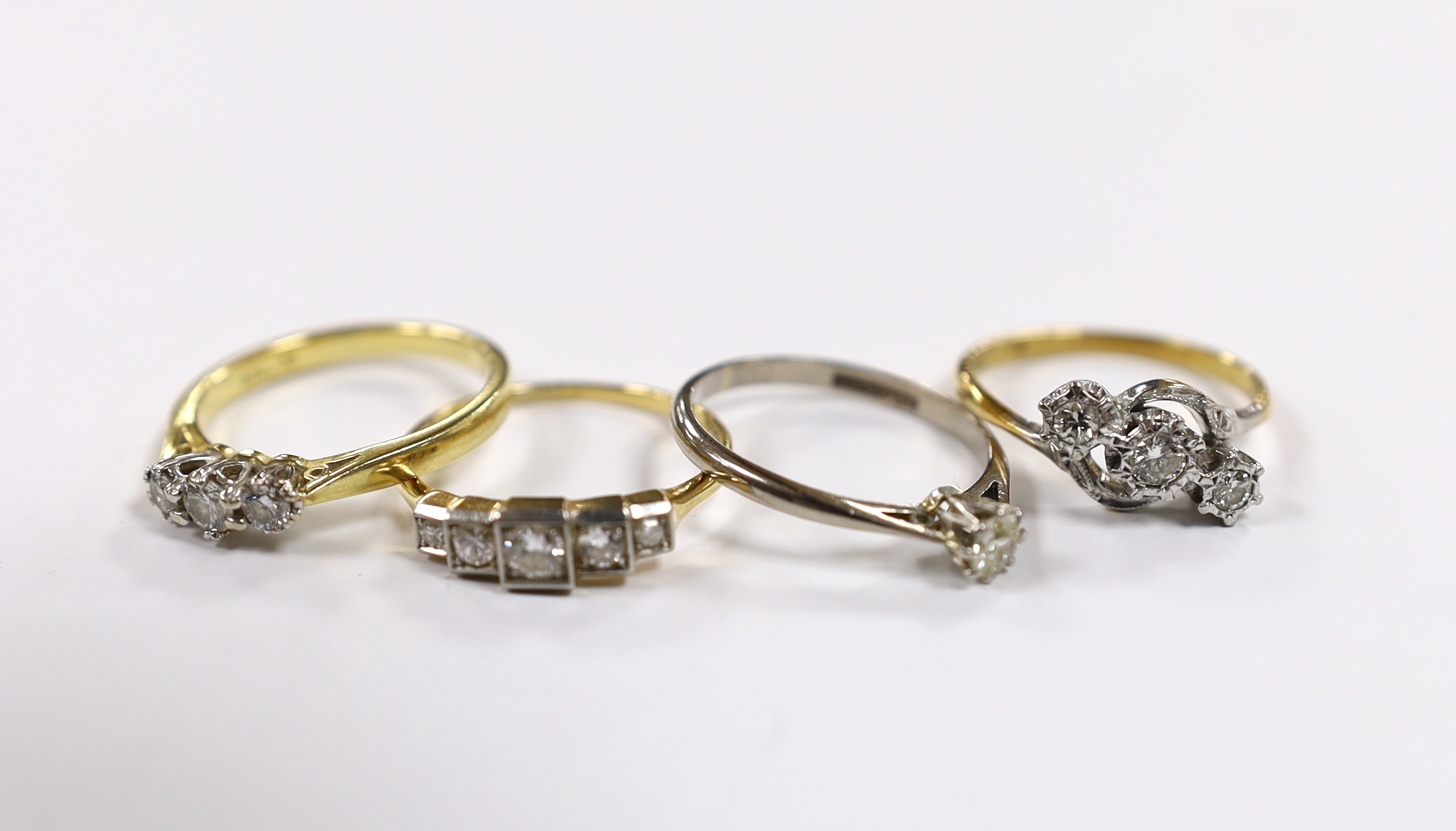 Four assorted 18ct and diamond set rings, including two three stone, a five stone and solitaire, gross weight 10.7 grams.